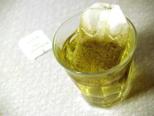 A cup of chamomile tea with loose chamomile flowers