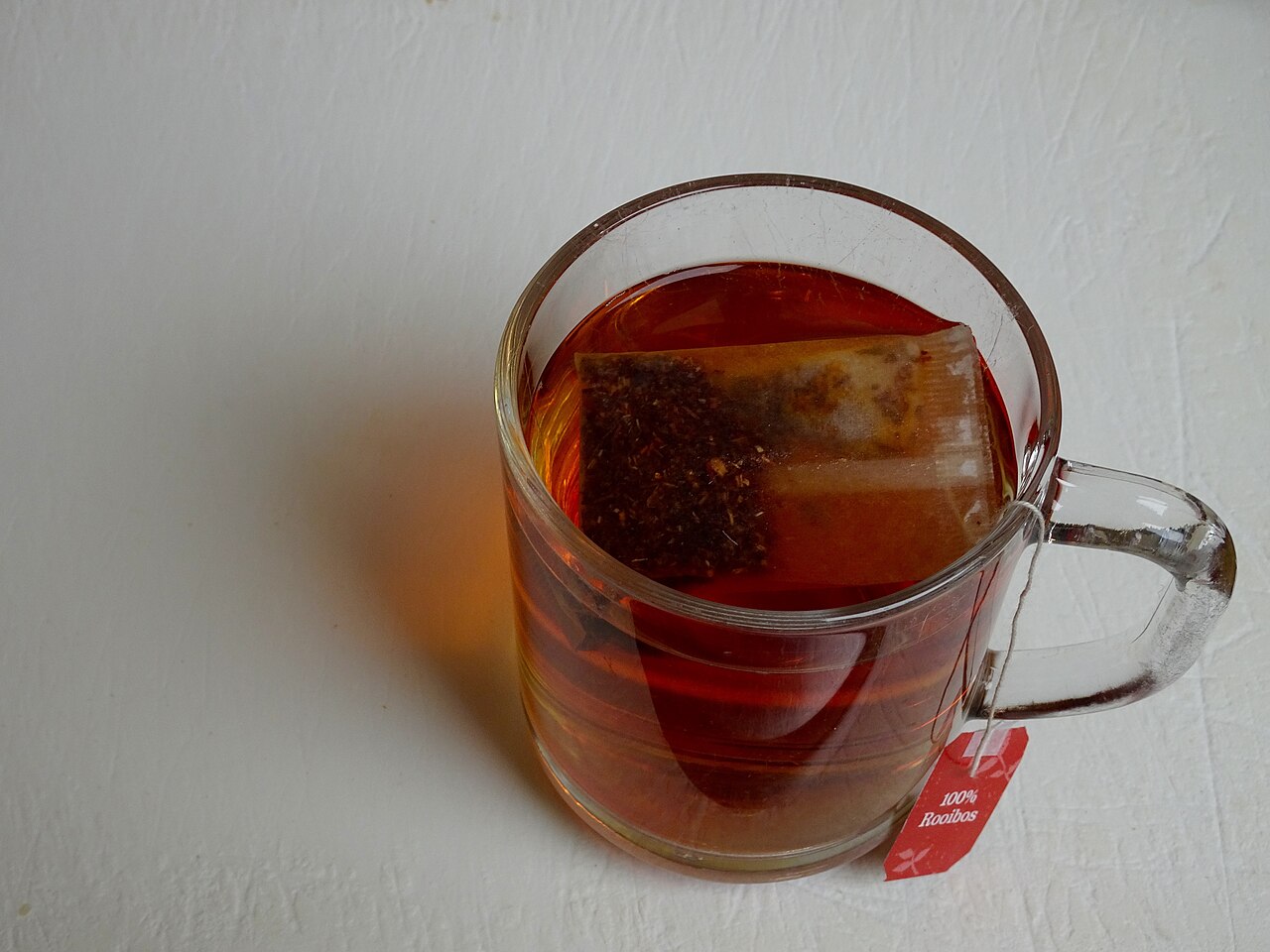 Your West Valley Guide to Our Herbal Tea Shop in Peoria 2 A clear glass mug of red rooibos herbal tea with a tea bag steeping